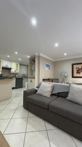 a living room with a couch and a kitchen at Surf & Serenity on Sea, by Jono & Erik in Jeffreys Bay