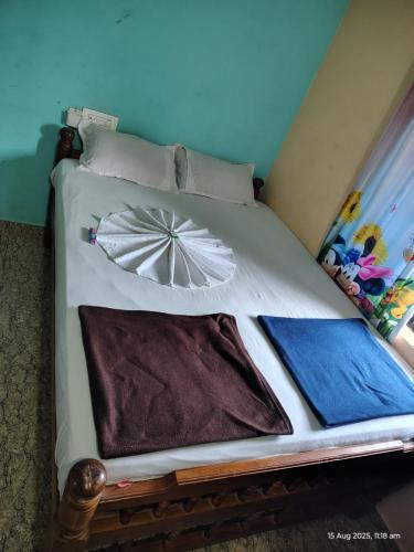 a bed with two pillows and an umbrella on it at DSouza Homestay in Māvalli