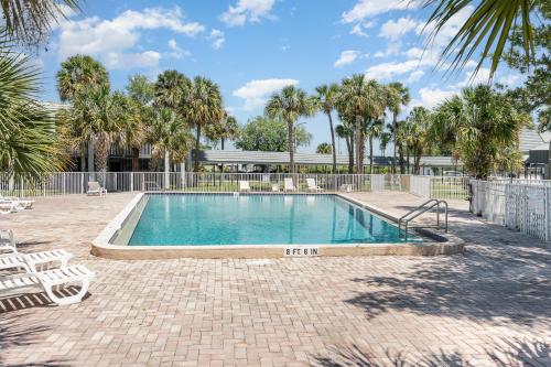 a swimming pool with chairs and a fence and palm trees at 2050 E IRLO BRONSON 1BED in Kissimmee