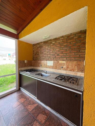 a kitchen with a sink and a brick wall at Amplio departamento con 2 habitaciones- Balcón hacia la pileta y estacionamiento in Miramar