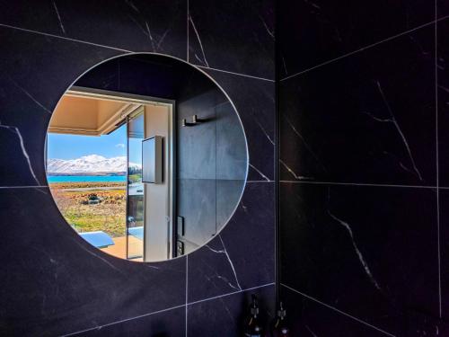 a bathroom with a round mirror on a black wall at Lakeview Tekapo in Lake Tekapo