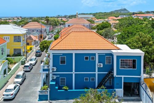a blue house with an orange roof on a street at Modern Apartment in the Heart of Willemstad in Willemstad