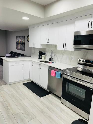 a kitchen with white cabinets and stainless steel appliances at Modern 2-bed 1-bath Suite in Calgary