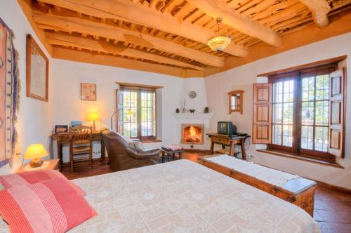 a bedroom with a bed and a living room with a fireplace at Cortijo Prado Toro in Pitres