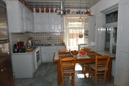 ミティムナにあるV. Molova, Molyvos, Lesvosの白いキャビネット、木製テーブルと椅子付きのキッチンが備わります。