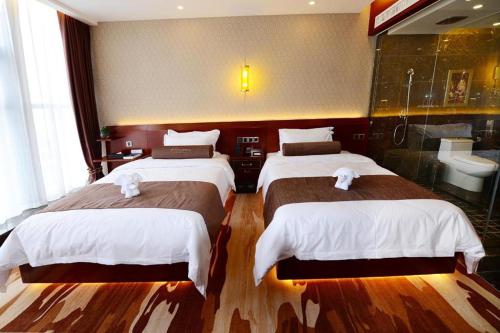 two beds in a hotel room with a bathroom at James Joyce Coffetel Golmud Huaxing Plaza Branch in Golmud