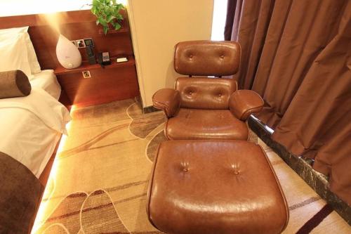 a brown leather chair sitting in a hotel room at James Joyce Coffetel Golmud Huaxing Plaza Branch in Golmud
