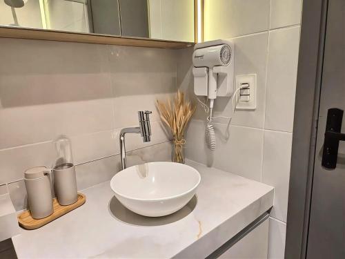 a bathroom with a sink and a hair dryer on a counter at Flat em Porto de Galinhas com Varanda, Aconchegante, Próximo ao Mar e ao Centro Comercial in Porto De Galinhas