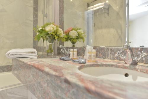 Un baño con lavabo y un espejo grande. en Hotel Suites Unic Renoir Saint-Germain, en París