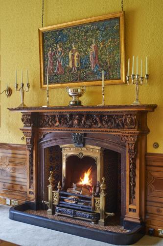 a fireplace in a room with a painting above it at Palé Hall in Bala
