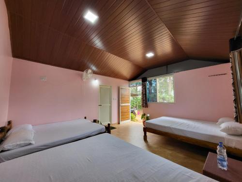 2 Betten in einem Zimmer mit Holzdecke in der Unterkunft CoffeeINN Homestay - Private Cottage, Water Activities and Home Food in Sakleshpur