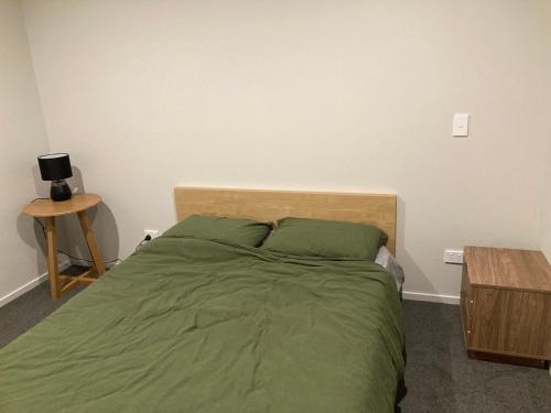 a bedroom with a bed with green sheets and a table at 408B Jervois Street Mayfair in Hastings