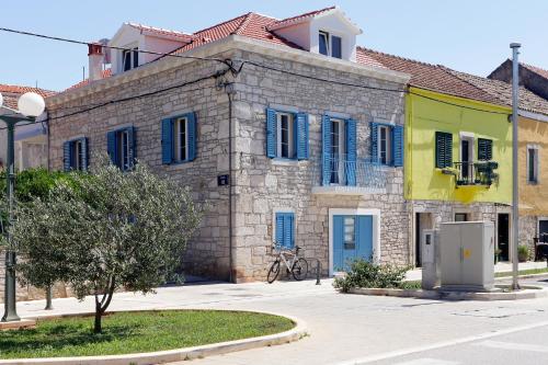 a stone building with blue shutters on a street at Luxory D-Rooms in Vela Luka