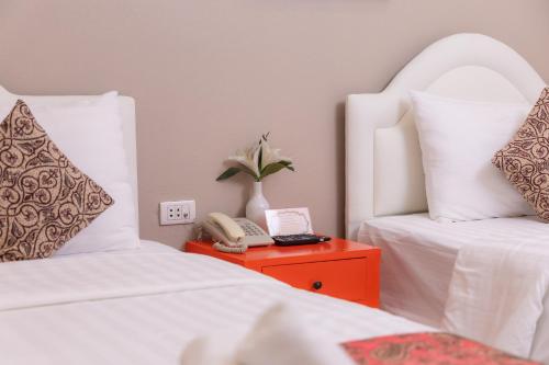 a room with two beds and a phone on a table at Rasa Boutique Hotel Chiang Rai in Chiang Rai