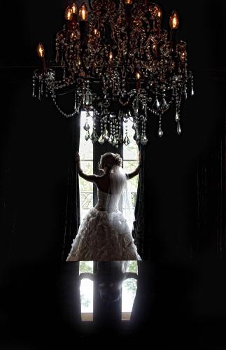 a bride standing in a window under a chandelier at Hotel ZaZa Dallas in Dallas