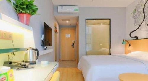 a hotel room with a bed and a desk with a sink at Vatica Hotel Hefei Yaohai Longgang Subway Station in Hefei