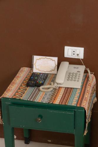 a green table with a telephone and a box on it at Rasa Boutique Hotel Chiang Rai in Chiang Rai