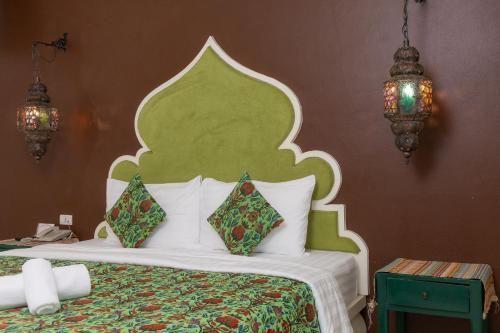 a bedroom with a bed with a green headboard and pillows at Rasa Boutique Hotel Chiang Rai in Chiang Rai