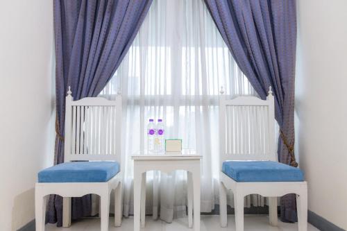 a table with two chairs and a window with blue curtains at Rasa Boutique Hotel Chiang Rai in Chiang Rai