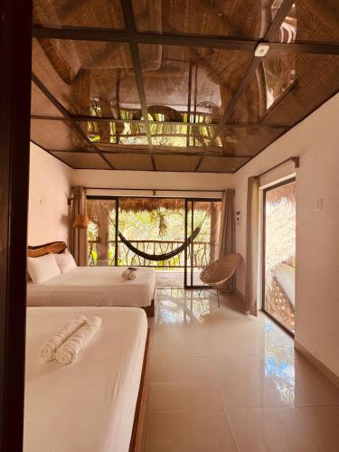 ein Schlafzimmer mit zwei Betten und einem großen Fenster in der Unterkunft Amarbacalar in Bacalar