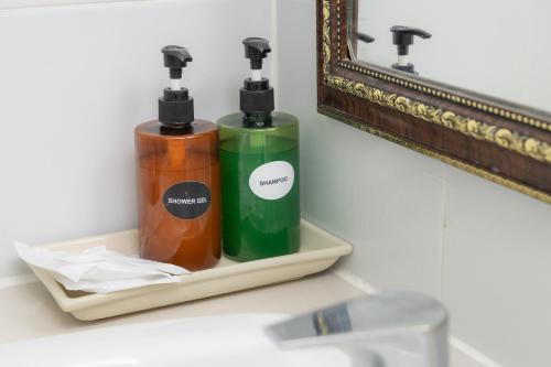 two bottles ofodorizers sitting on a shelf next to a mirror at Rasa Boutique Hotel Chiang Rai in Chiang Rai