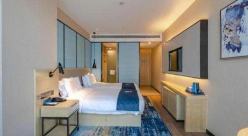a hotel room with a large bed and a desk at Echarm Hotel Hefei West Qilitang Metro Station in Hefei