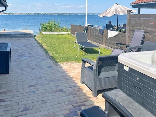 a patio with chairs and an umbrella and the water at 4 person holiday home in Middelfart-By Traum in Middelfart