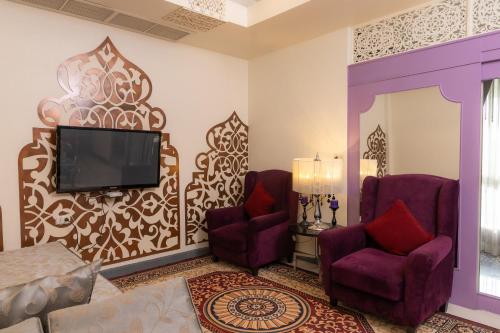 a living room with two chairs and a flat screen tv at Rasa Boutique Hotel Chiang Rai in Chiang Rai