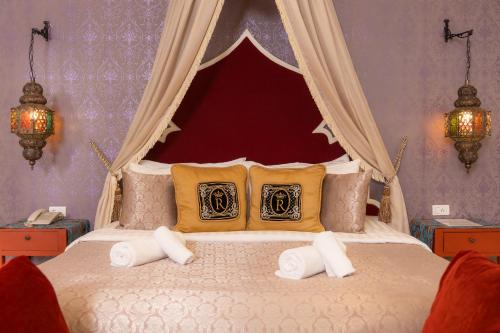 a bedroom with a canopy bed with two pillows at Rasa Boutique Hotel Chiang Rai in Chiang Rai