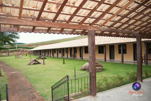 a building with a fence and a grass yard at Hotel Fazenda Topada in Baependi