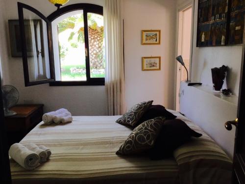 a bedroom with a bed with pillows and a window at Villa Gandamar in Santa Teresa Gallura