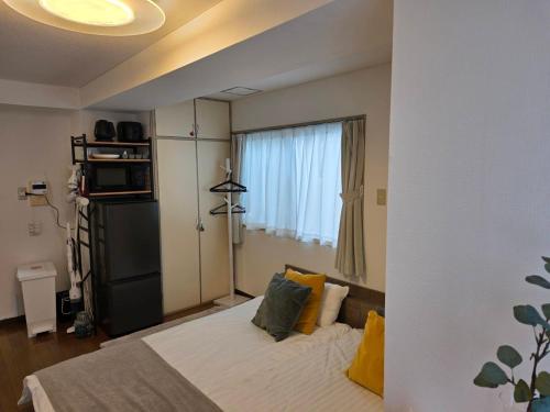 東京にあるホテルレスポワール301の黄色い枕と窓のあるベッドのある寝室