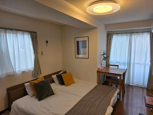 a bedroom with two beds and a desk and windows at ホテルレスポワール301 in Tokyo