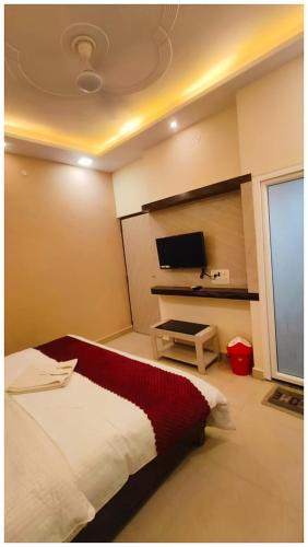 a bedroom with a bed and a flat screen tv at The Aura Hotel Prakash Retreat - Near Kashi-Vishwanath Temple And Ganga Ghat With #Lift #Wi-fi-Restaurant- A Premium Hotel in Varanasi in Varanasi