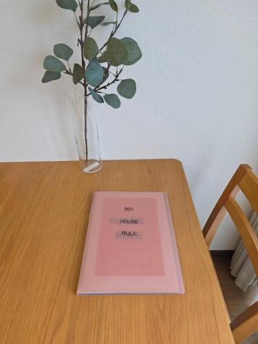 a book sitting on a wooden table with a vase at ホテルレスポワール301 in Tokyo