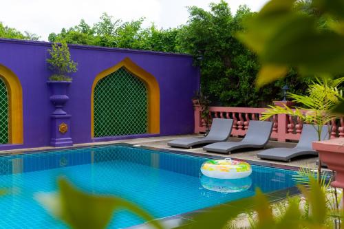a swimming pool with two chairs and a purple building at Rasa Boutique Hotel Chiang Rai in Chiang Rai