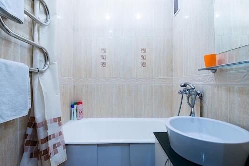 y baño con bañera blanca y lavamanos. en Studiominsk 8 Apartments, en Minsk