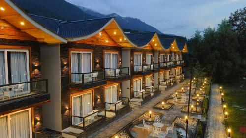 a building with a courtyard with tables and lights at Shivalaya Retreat - A River Side Resort in Manāli