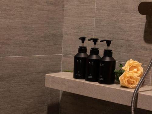 a group of four black bottles on a shelf in a bathroom at Atour Hotel Jinan Tangyan Century Avenue in Jinan