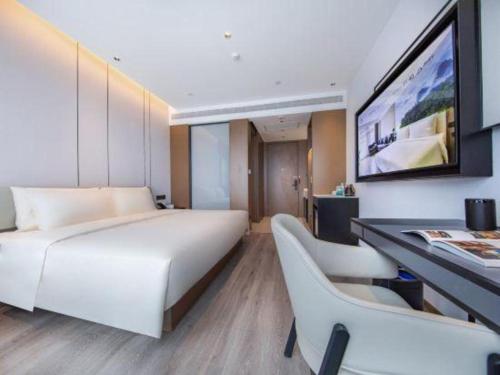 a bedroom with a large white bed and a desk at Atour Hotel Jinan Tangyan Century Avenue in Jinan