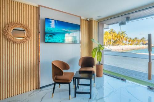 two chairs and a table in a room with a view of the beach at Swarn by Hawks Hotels Kamadhoo Baa Atoll in Baa Atoll