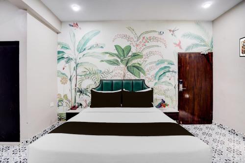 a bedroom with a large bed with a tropical wallpaper at Super Townhouse Chandpole Metro Station Formerly Hotel Raghuraj Palace in Jaipur