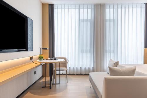a hotel room with a tv and a couch and a table at Jinyi Select Hotel Hohhot Juhaicheng International Convention and Exhibition Center in Hohhot