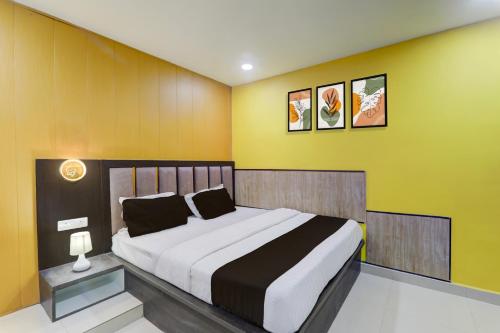 a bedroom with a large bed with yellow walls at Super Hotel O Medical College Basaratpur Gorakhpur in Gorakhpur