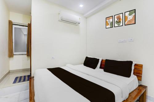 a bedroom with a bed with white walls at Super Hotel O IIM Road Lucknow in Lucknow