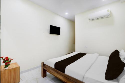 a white bedroom with a bed and a tv at Super Hotel O IIM Road Lucknow in Lucknow