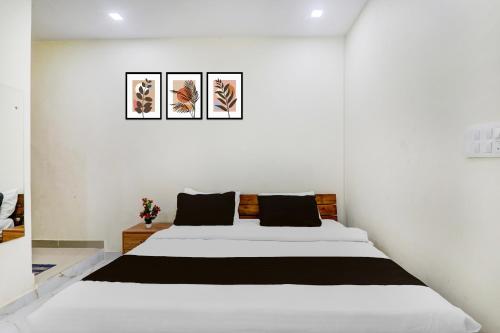 a white bedroom with a large bed with black pillows at Super Hotel O IIM Road Lucknow in Lucknow