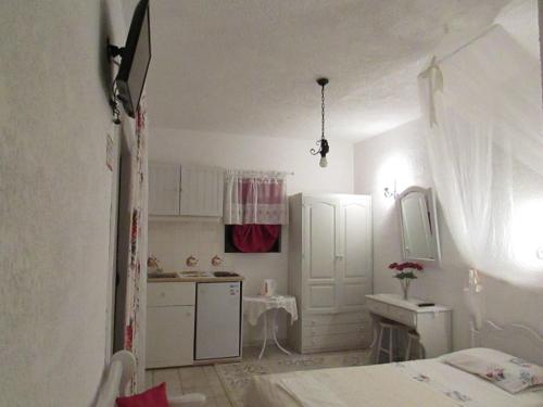 a small white room with a bed and a kitchen at Castellino Studios in Faliraki