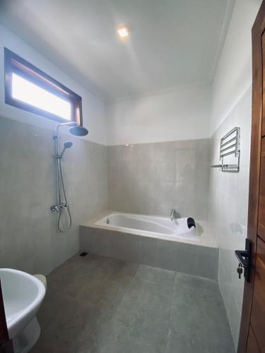 Un baño blanco con bañera y lavabo. en Villa Vina by MentariPro Bali, en Singaraja