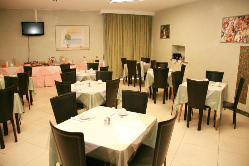 a dining room with white tables and black chairs at Hotel Niagara Rimini in Rimini
